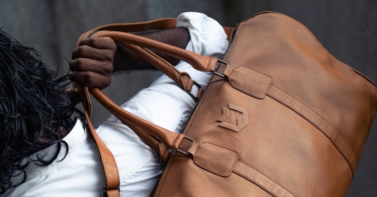 Einseitig getragene braune Ledertasche an männlicher Hand