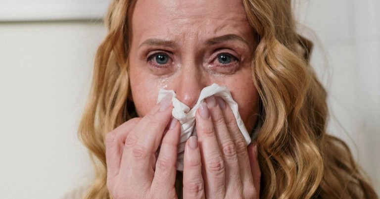 Symptome von Pollenallergie: Frau hält sich ein Taschentuch an die Nase