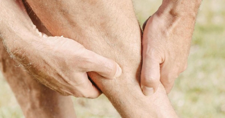 Mann hält sich das schmerzende Bein wegen Muskelschmerz