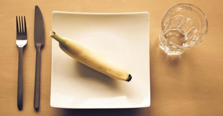 Banane auf weißem Teller – einzelne Banane auf quadratischem, weißen Teller