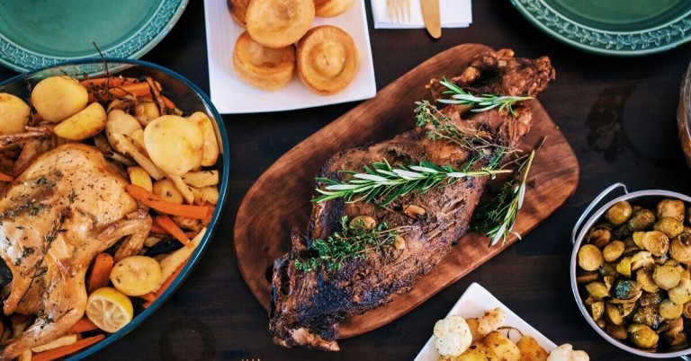 Festessen mit Braten, Rosmarin, Yorkshire Pudding und Gemüse auf einem festlich gedeckten Tisch