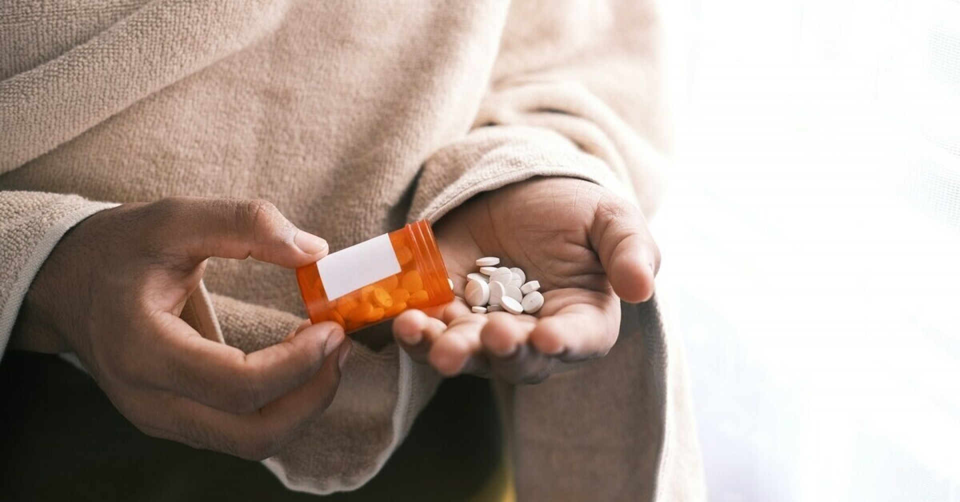 Hand hält Tabletten und Medikamentendose, Nahaufnahme von Tabletten