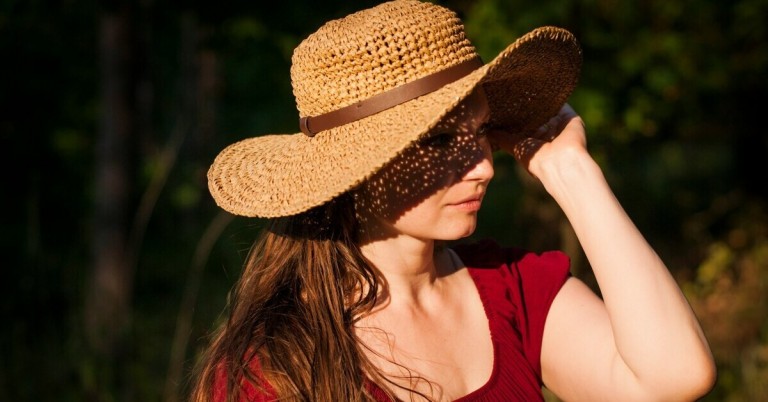 Frau mit Strohhut als Sonnenschutz im Sommer