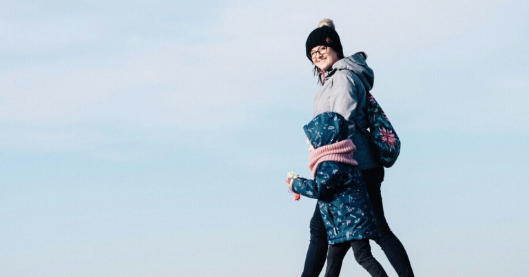 Zwei Personen beim Spaziergang an einem klaren Tag, beide warm angezogen