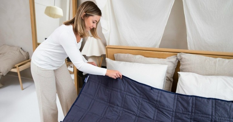 Frau bezieht ein Bett mit moderner Bettwäsche in einem gemütlichen Schlafzimmer