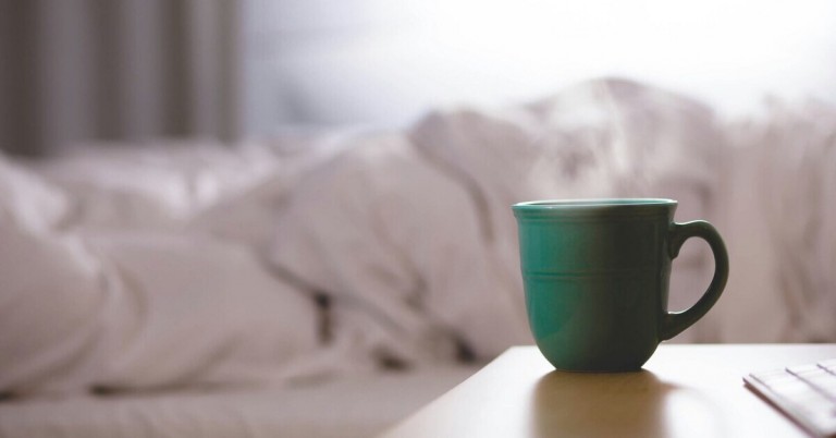 Grüne Teetasse auf einem Tisch vor einem unscharfen Hintergrund, entspannte Morgenstimmung mit Tee