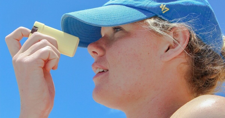 Kind trägt Sonnencreme-Stick auf Gesicht auf, Sonnenschutz im Sommer