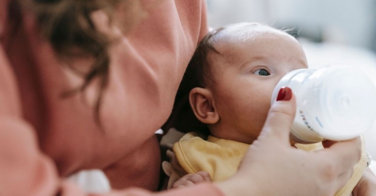 Baby wird von einer Frau mit der Flasche gefüttert – kind futtern