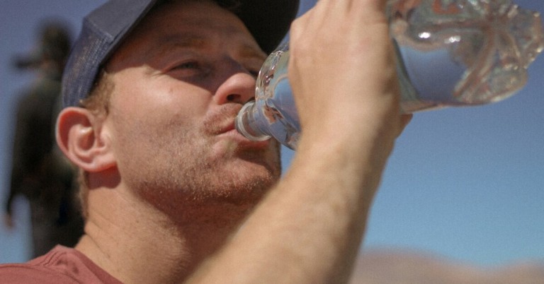 Mann trinkt Wasser bei Hitze, um sich zu erfrischen und hydratisiert zu bleiben